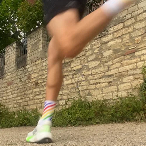 Jogger mit bunten Laufsocken läuft an Steinmauer im Freien, Sport, Fitness, Laufen