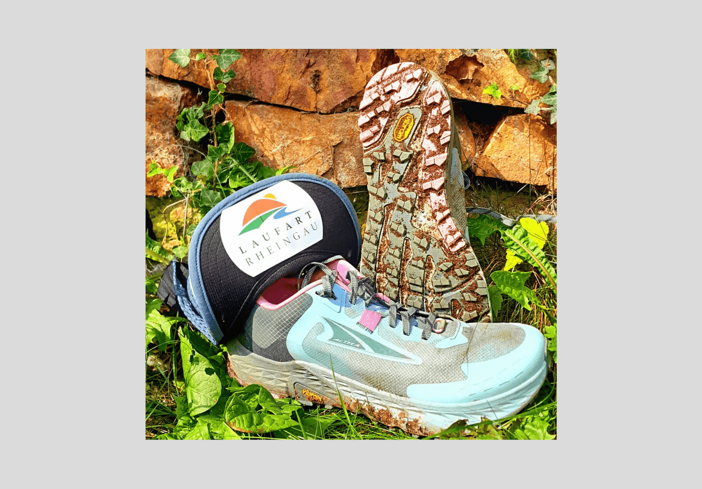 Altra Timp Laufschuh mit Mütze Laufart Rheingau auf Gras vor Steinmauer