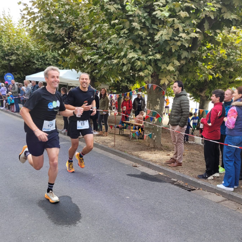 Zwei Läufer beim Eltviller Familienlauf auf Straße, Zuschauer am Straßenrand, bunte Wimpel