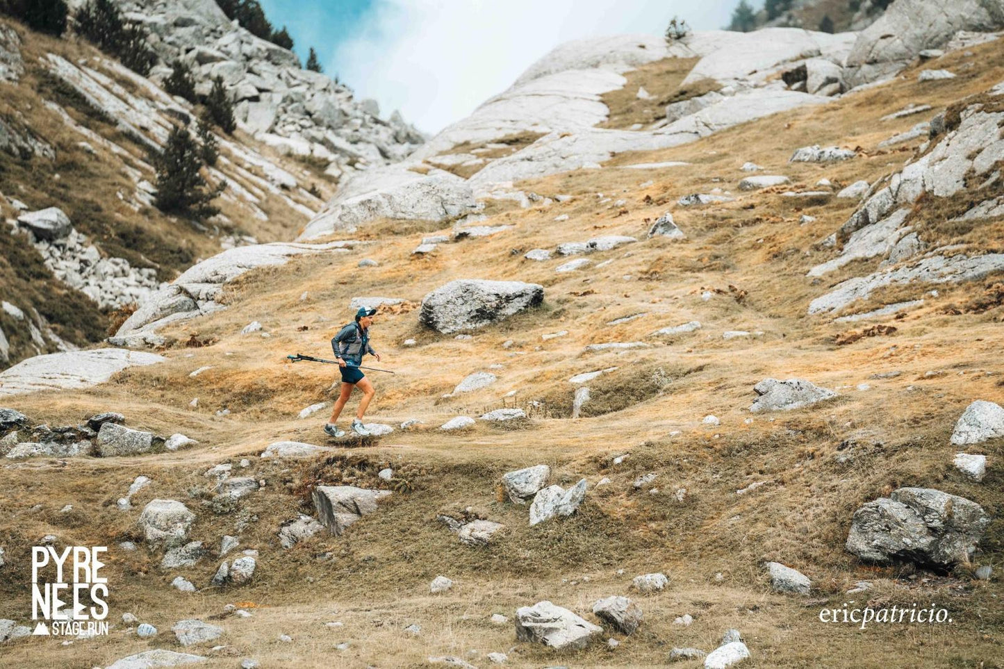 Trailrunner in Sportkleidung läuft mit Stöcken in den felsigen Pyrenäen beim Pyrenees Stage Run