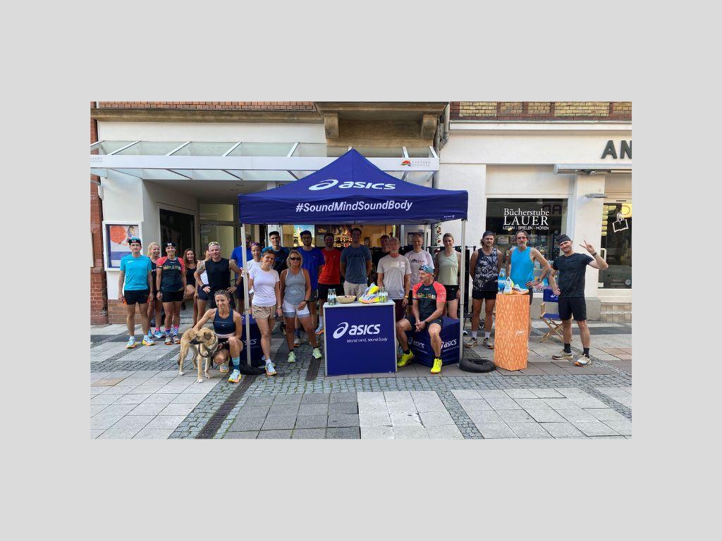 Lauftreff Gruppe vor Asics Pavillon in Eltville, Sportler in Laufkleidung auf Gehweg