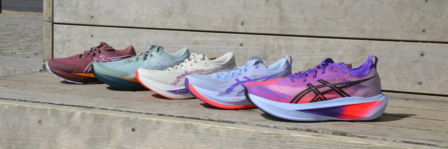 Fünf bunte Asics Laufschuhe auf Holzboden, Sport Turnschuhe Outdoor Szene