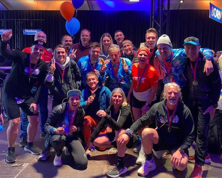 Läufergruppe mit Medaillen beim Venlo Lauf-Event, fröhliche Stimmung, Indoor-Location