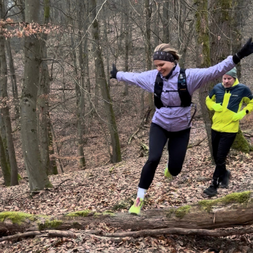 Trailrunner im Wald bei Wiesbaden Rheingau, balanciert über Baumstamm beim Traillaufen